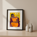 Framed artwork of a black woman in an orange dress with white flowers on a beige wall.