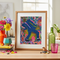 Framed colorful artwork of an abstract man dancing on a table with decorative items