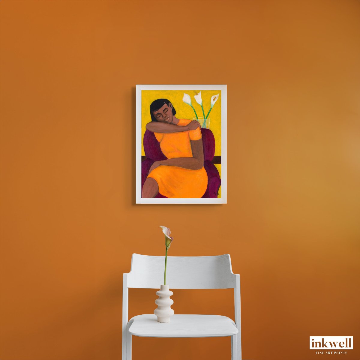 A Quiet Moment print Framed in a white wood frame above a white chair in a n orange room