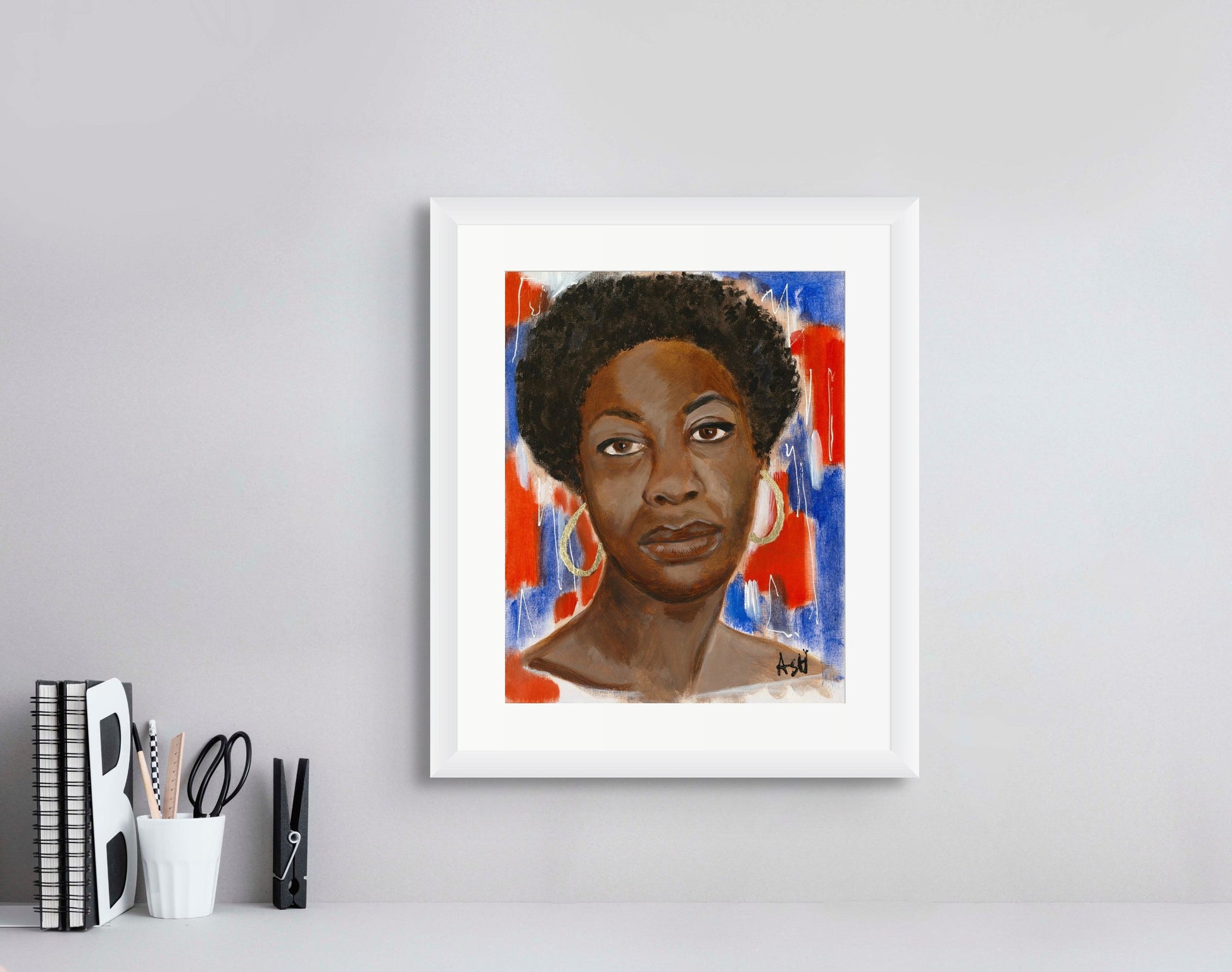 Portrait of Nina Simone framed in a crisp white frame with white matting. The artwork features dynamic red, white, and blue tones, highlighting her influential role in music and civil rights, elegantly presented to enhance its striking colors.