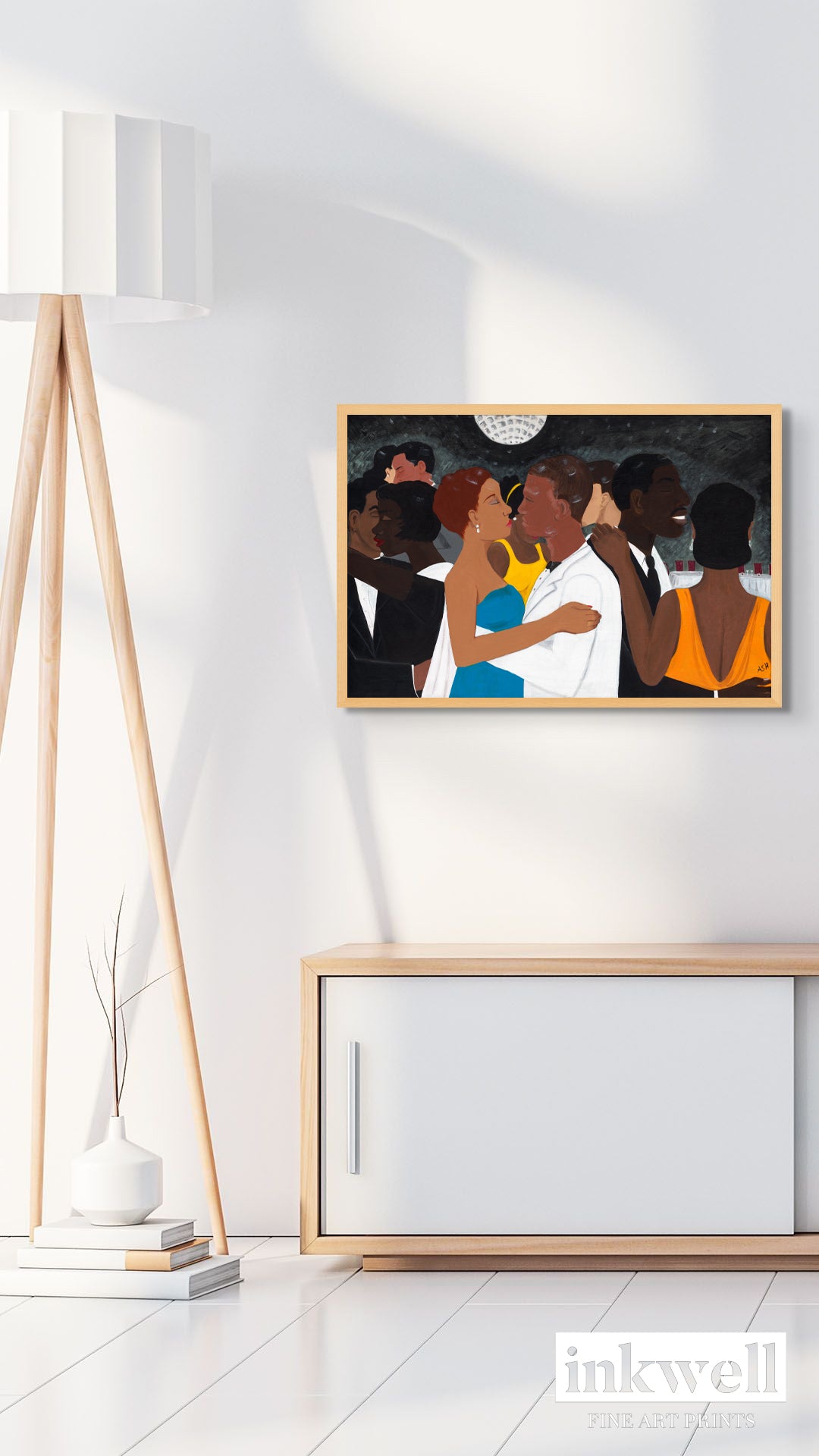 'Black Tie Affair' fine art print: Couple in blue and yellow dress, white suit, surrounded by elegantly dressed figures against a monochromatic background, framed in oak-colored wood, on a white wall above a white and natural wood media center.