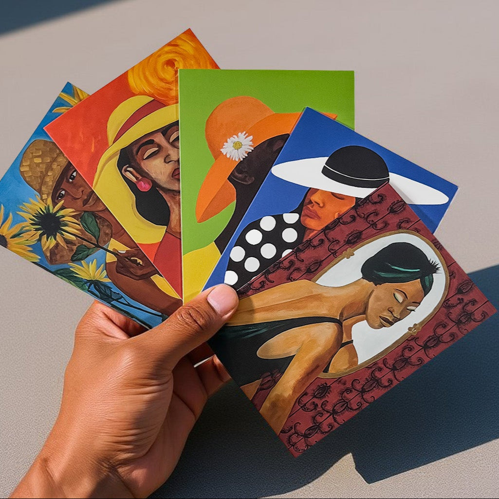 Hand holding a stack of colorful african american art greeting cards on a neutral background