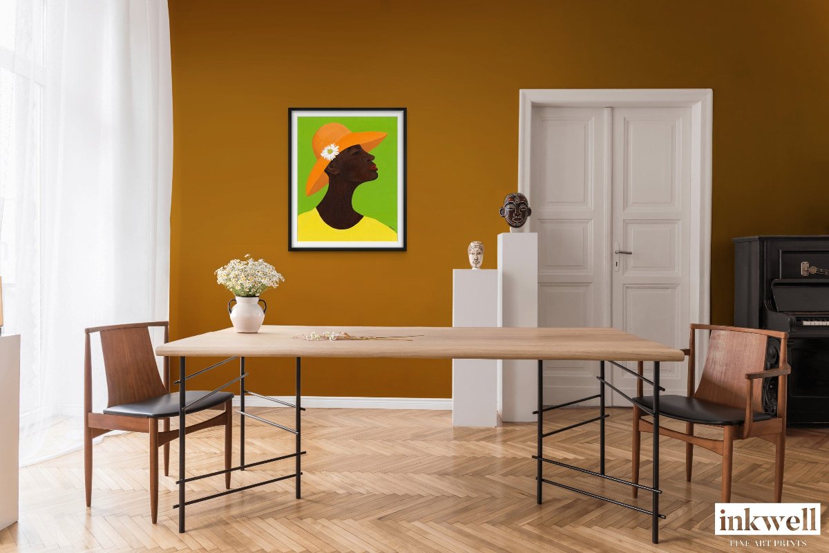 giclee art print 'Annabelle's New Hat': African American woman in yellow outfit, orange hat with daisy, against green, on living room wall above large dining table with vase of dried flowers.