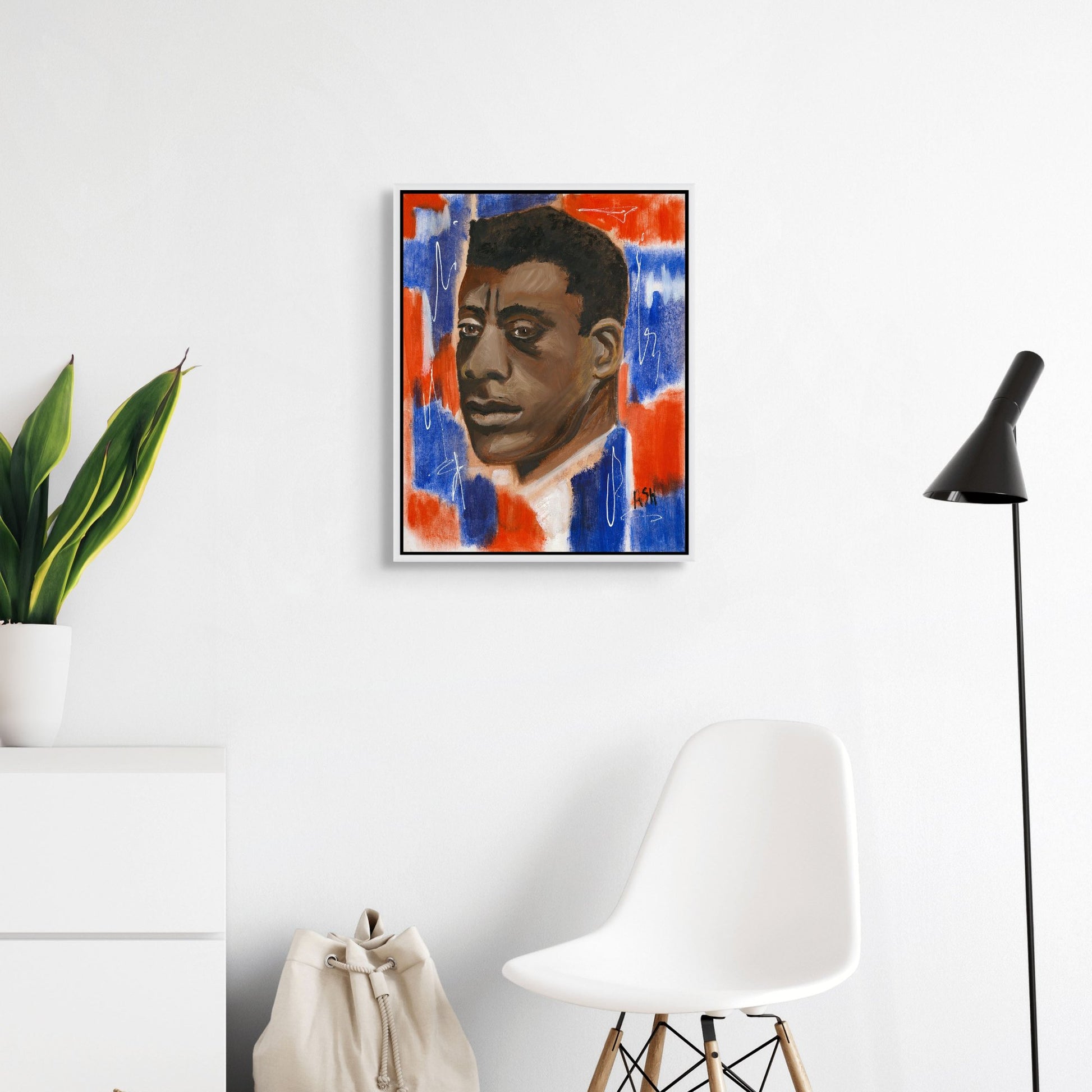 Framed stretched canvas print of 'Red, White & Blues - James Baldwin,' set in a sleek white frame. The artwork features Baldwin against a vibrant red, white, and blue backdrop, capturing his impactful role in literature and civil rights, with the white frame offering a clean, contemporary look.