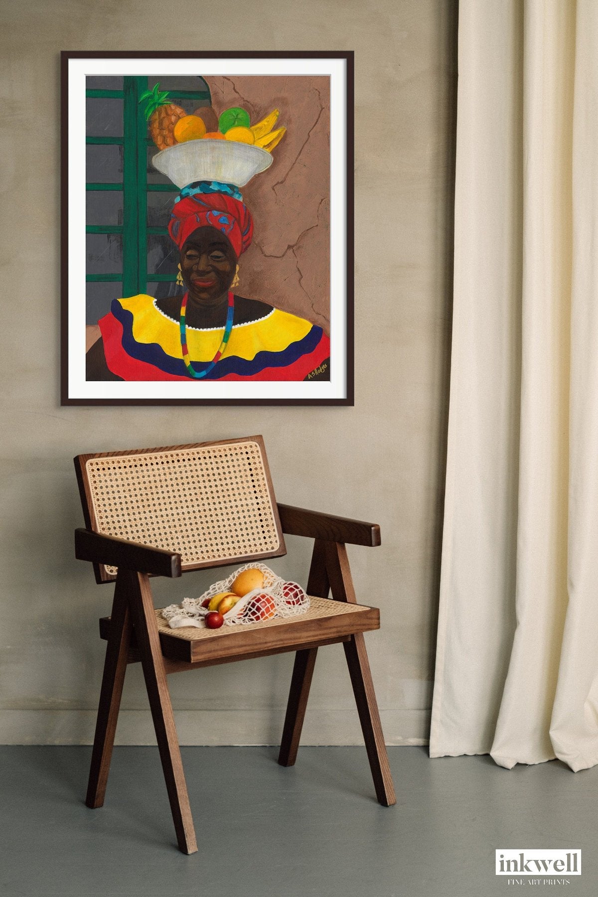 black art Print 'Hey Lady' By Antionette Simmons Hodges depicting a Colombian Fruit Vendor hung above a wood and wicker chair