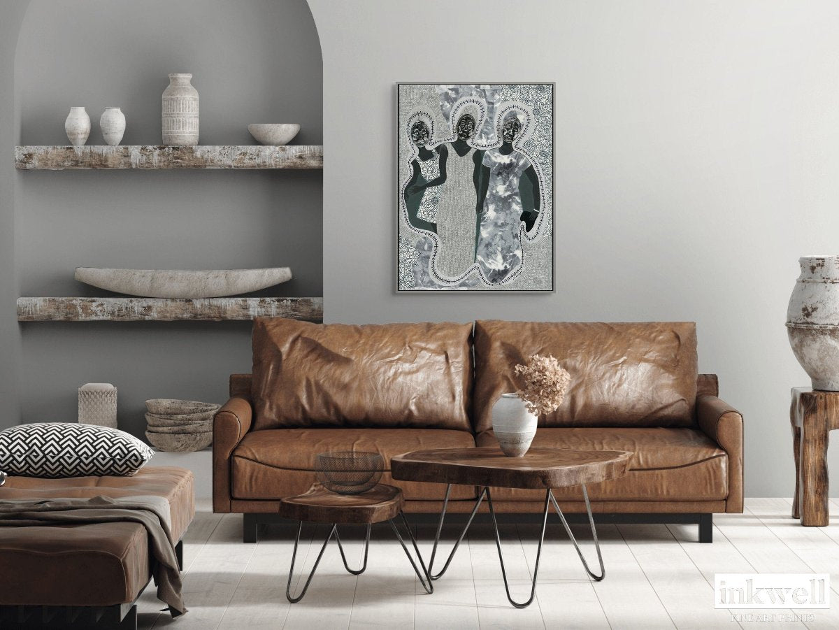 Mirror Mirror' art print: Three elongated female silhouettes with embossed metal gift tags as faces, positioned against a patterned gray and white background with decorative borders, representing themes of self-reflection and identity. shows in living room above leather sofa