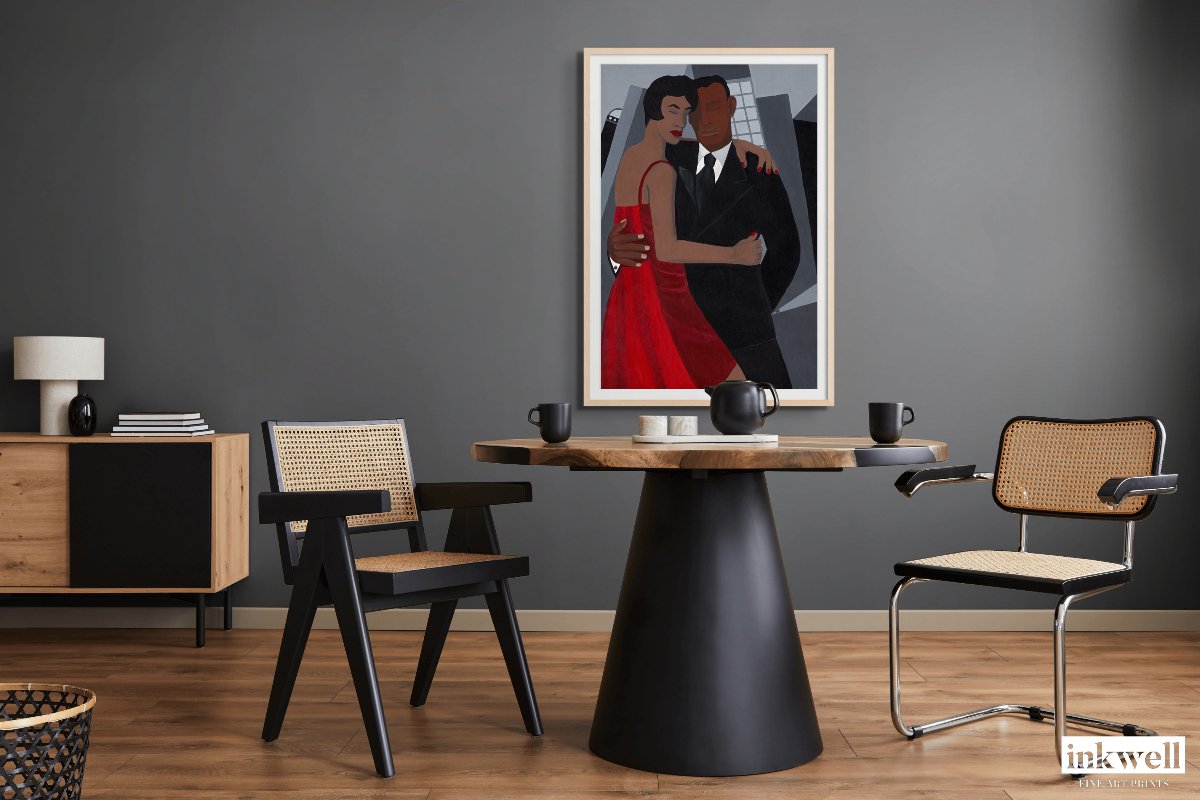 'Night on the Town' art print: Elegantly dressed couple, woman in a red dress and man in a black suit, embracing against a stylized urban backdrop with abstract buildings, capturing a romantic and celebratory evening atmosphere. framed in a natural wood with white mat placed above a circular dining table.