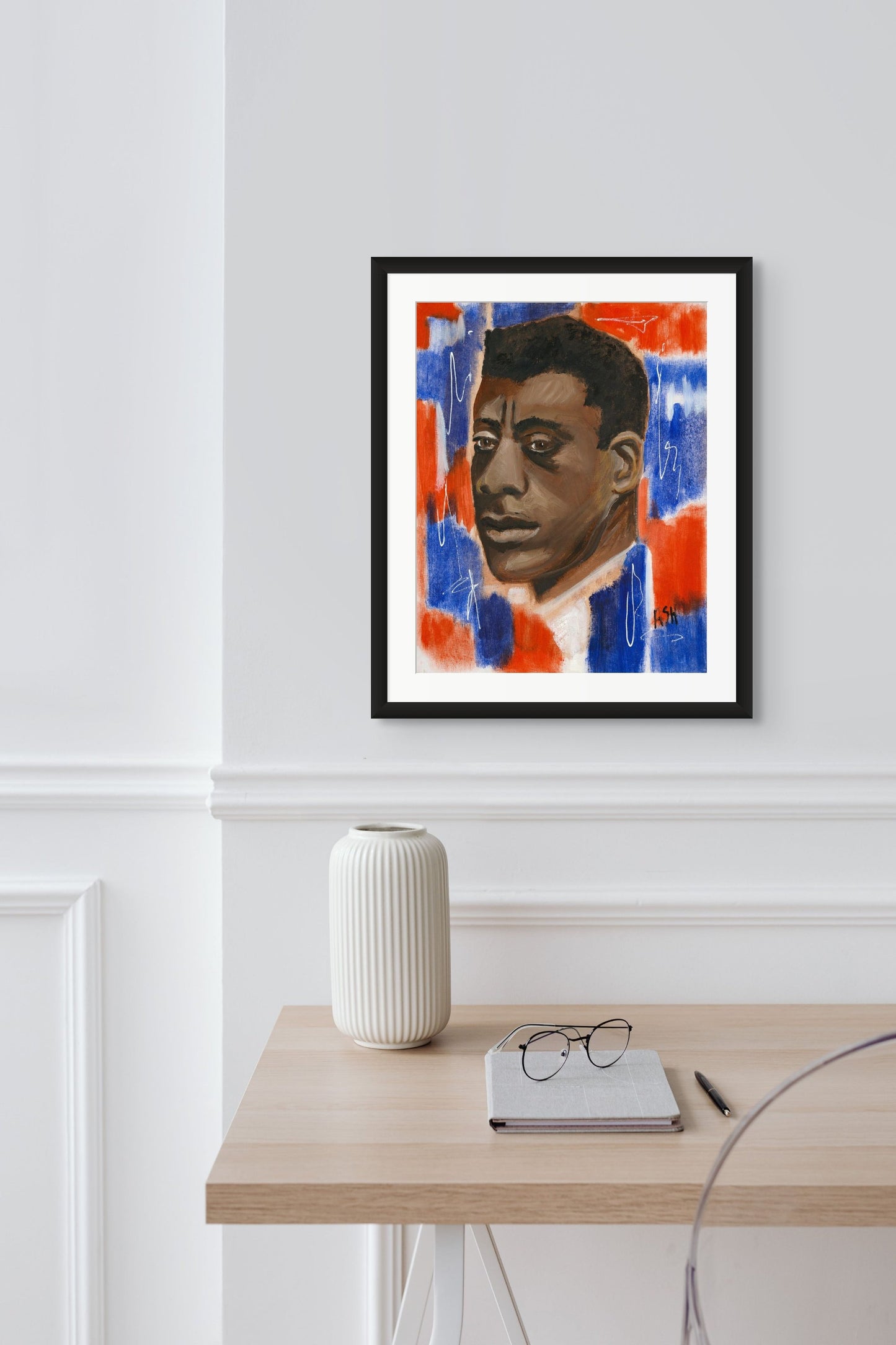 Portrait of James Baldwin in a sophisticated black frame with white matting. The artwork is infused with dynamic red, white, and blue tones, emphasizing Baldwin's significant cultural and literary influence, beautifully framed to accentuate its striking colors