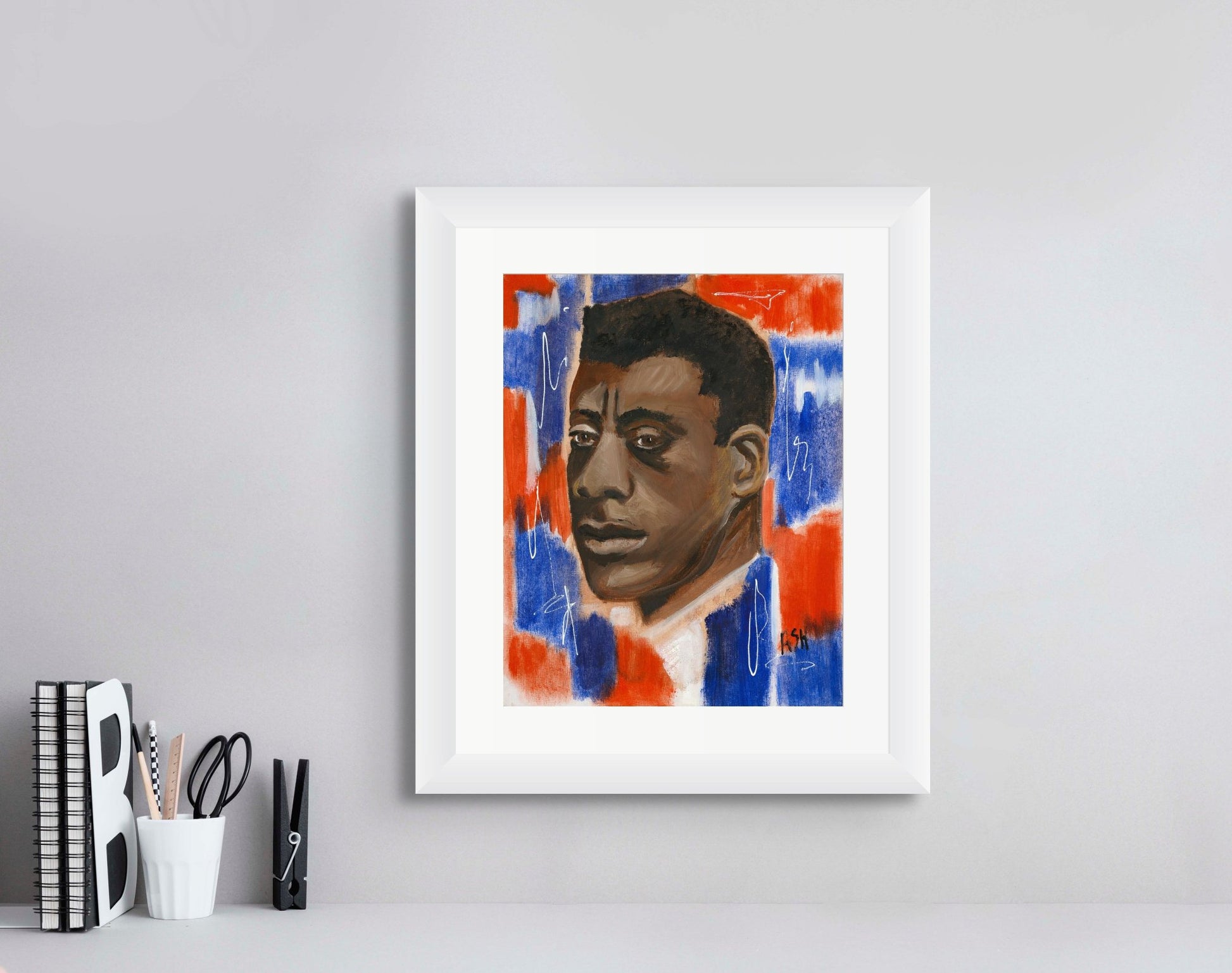 Portrait of James Baldwin framed in a sleek white frame with a white matting. The artwork features vibrant red, white, and blue tones, highlighting Baldwin's influential role in literature and civil rights, elegantly presented to enhance its visual impact.