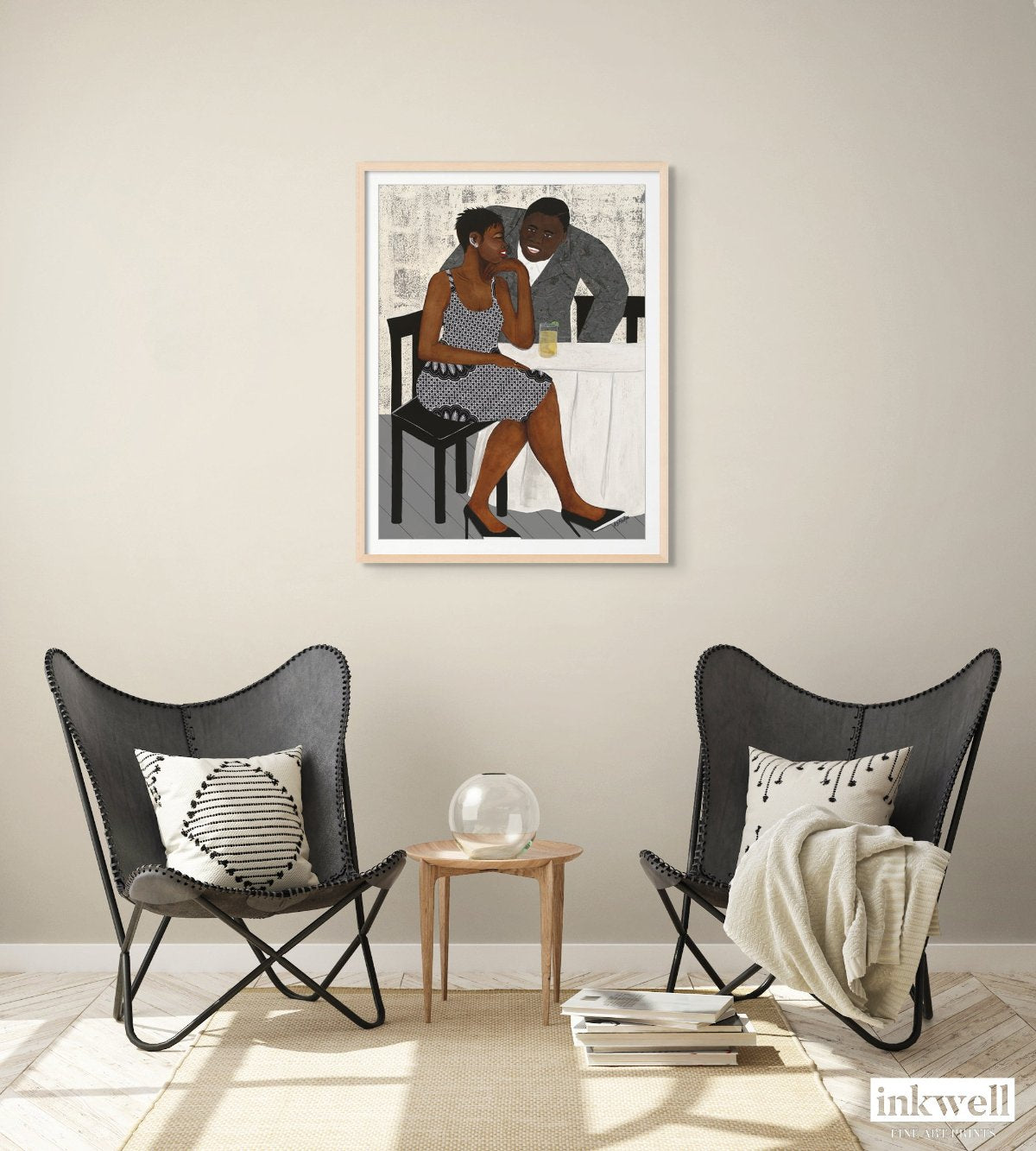 'The Conversation' paper print: Black couple sharing a moment of connection, featuring the woman's bold African-inspired attire and the man's warm smile, displayed on high-quality fine art paper. shown in natural wood frame with white mat above a set of chairs.