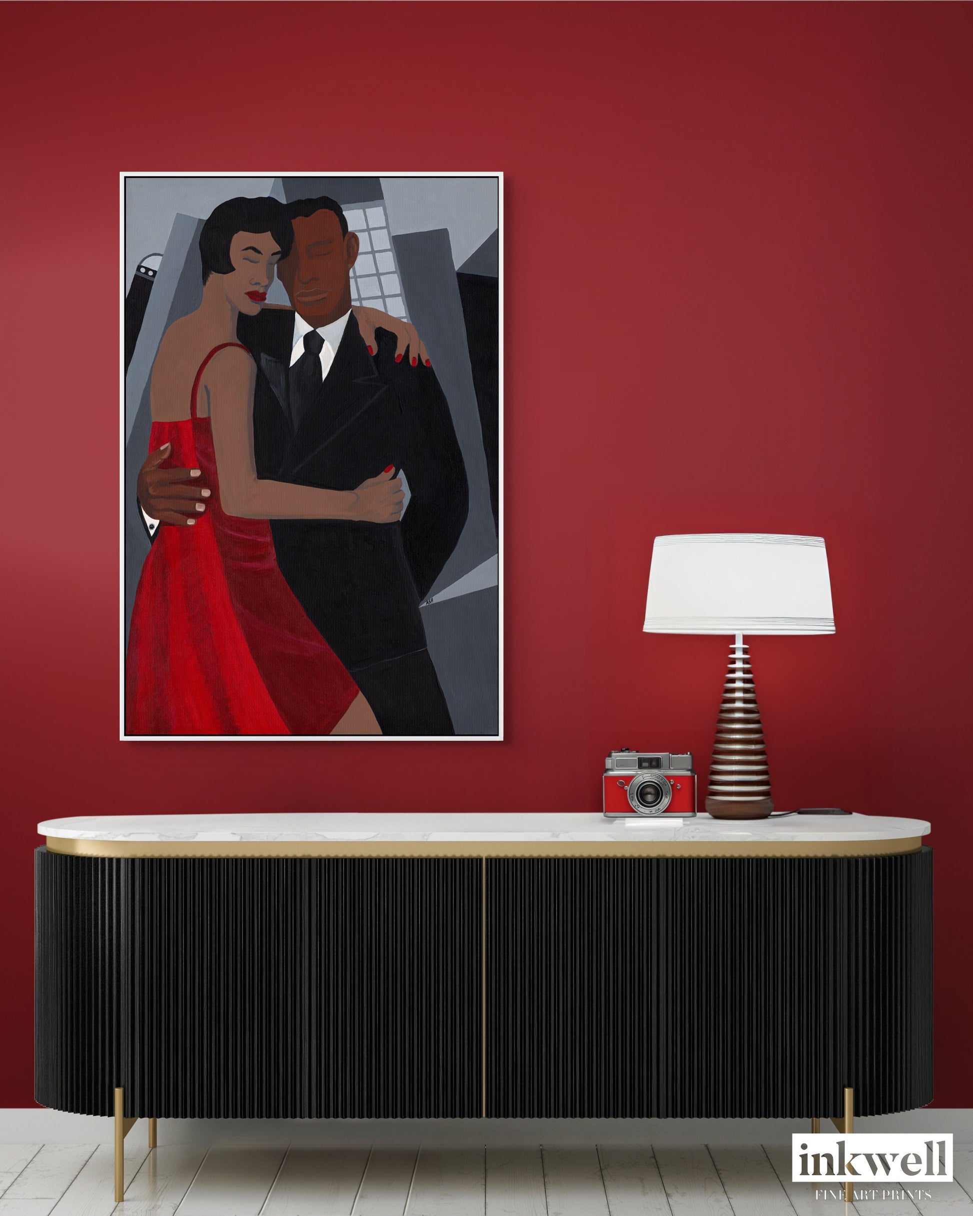 Night on the Town' art print: Elegantly dressed couple, with the woman in a red dress and the man in a black suit, embracing against a stylized urban backdrop with abstract buildings, capturing a romantic and celebratory evening atmosphere, framed in white wood.